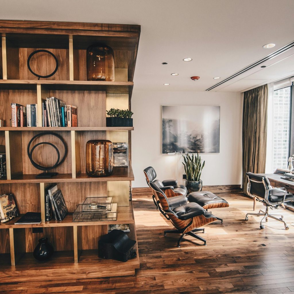 pexels-photo-2883049-2883049 Stylish office space featuring a wooden bookshelf and a minimalist desk setup, ideal for work.